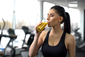 Femme sportive dans un gym buvant un jus préparé au bar santé.