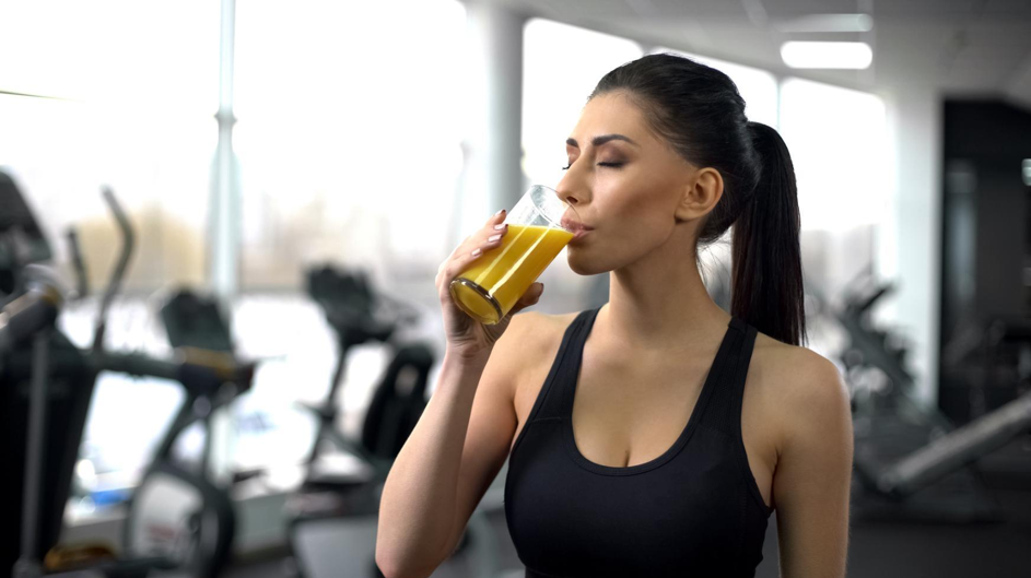 Femme sportive dans un gym buvant un jus préparé au bar santé.